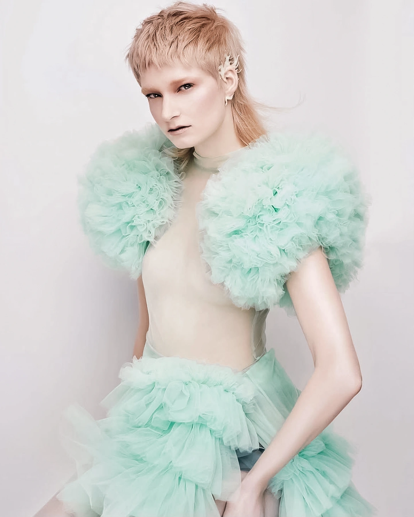 Model facing the camera in a blue-green feathered look. Styling assistance by Storm Nijhuis, with styling by Annet Veerbeek.